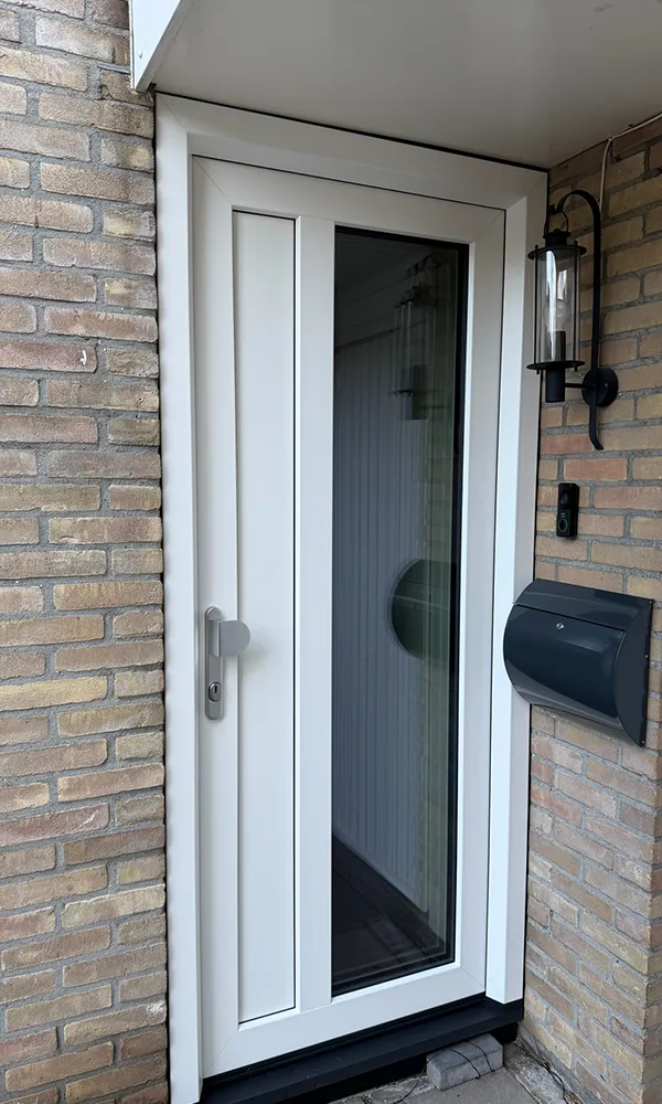 Witte kunststof voordeur met smalle glasstrook in bakstenen gevel, voorzien van modern beslag en onderhoudsarme afwerking.