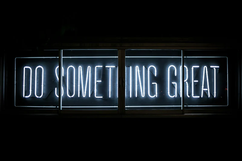 Neon sign with the words 'Do Something Great' glowing in the dark.