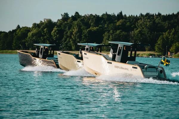 electric boats cruising on the water near a forest shoreline.