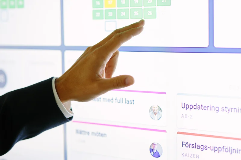 Close-up of a hand interacting with a digital board displaying tasks and updates