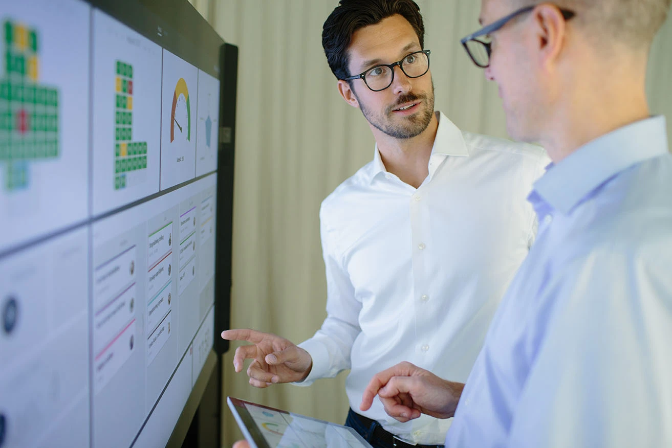 Two colleagues reviewing performance data on a Mevisio board