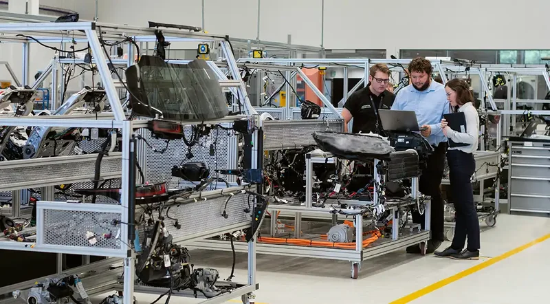 Manufacturing team reviewing information beside a vehicle assembly station