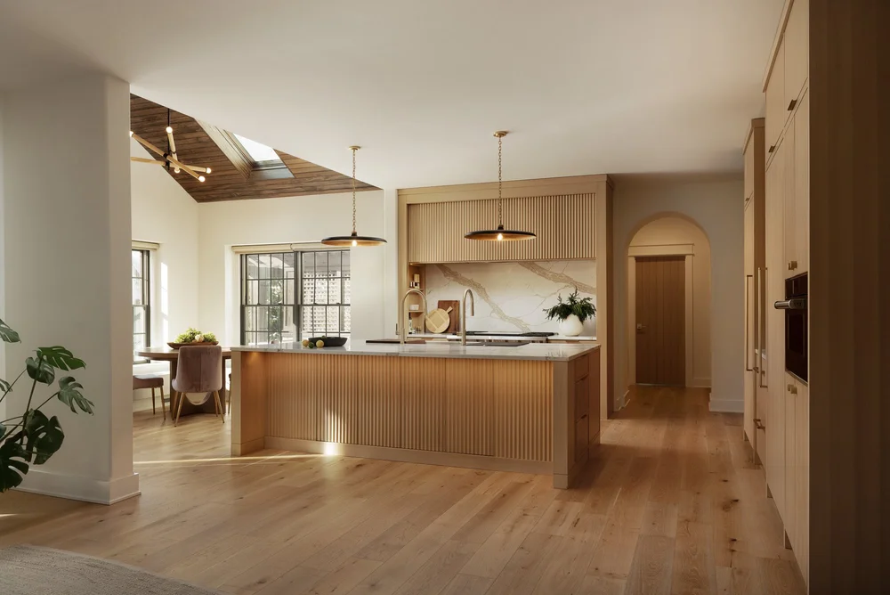 Expanded kitchen with large wood island, white stone backsplash, and open layout made possible by a room addition