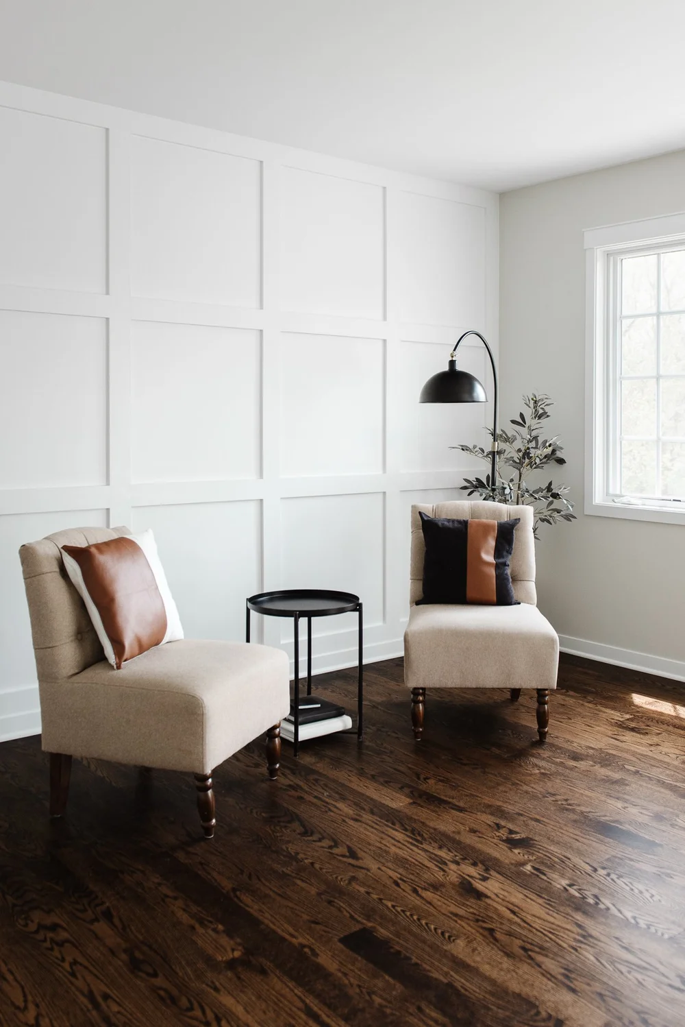 Former bedroom converted into a bright reading nook with lounge chairs and paneled walls