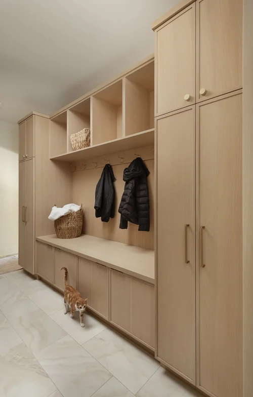 Mudroom drop zone with wood bench, coat hooks, and cubbies at the garage entry