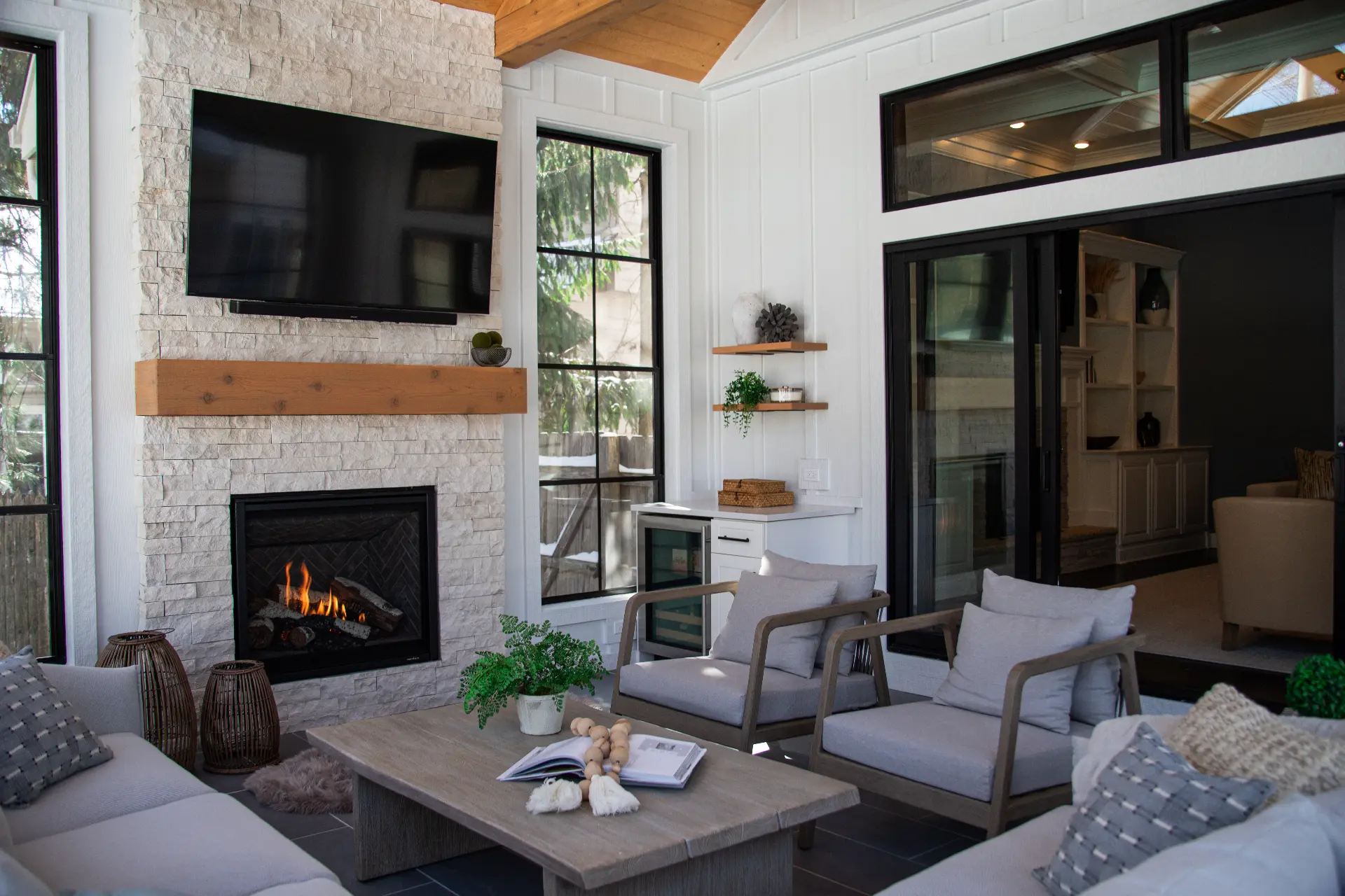 Sunroom addition with stone fireplace, black-framed windows, and casual seating
