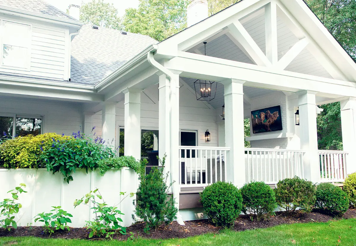 Covered porch addition with white columns and gable trim connected to the existing home