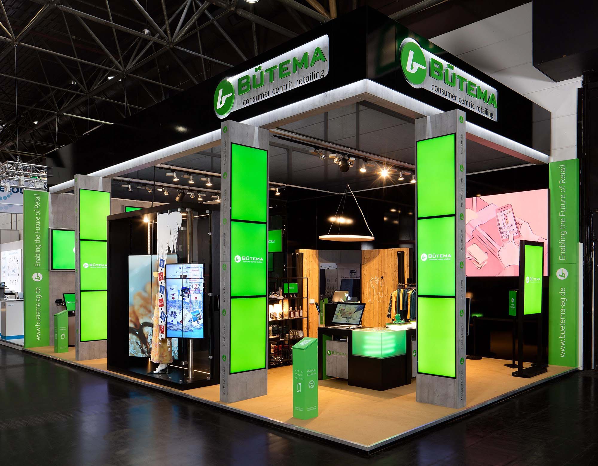 Moderne Messestandsstruktur mit grünen Displays und Bütema-Logo, das Einzelhandelslösungen präsentiert.