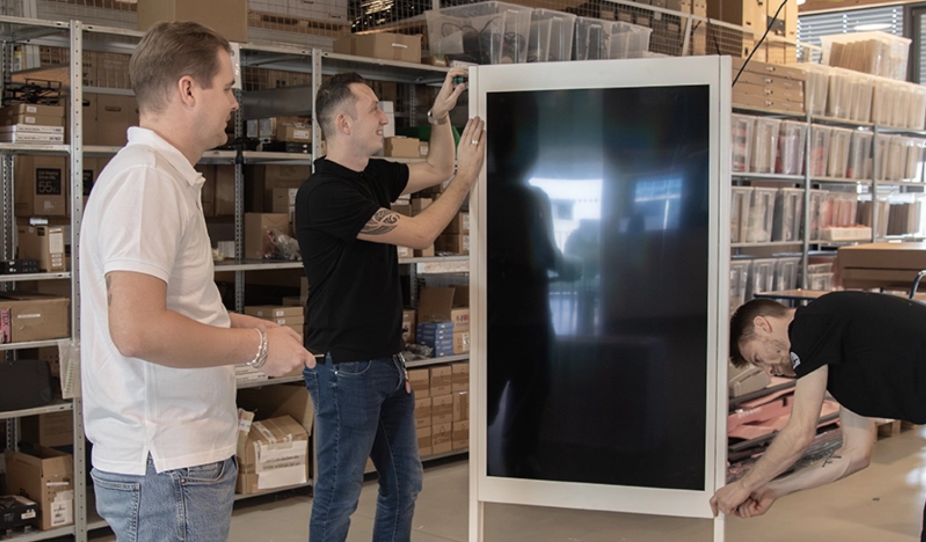Zwei Techniker im Lager der Bütema AG bei der Vorbereitung eines Digital Signage Screens
