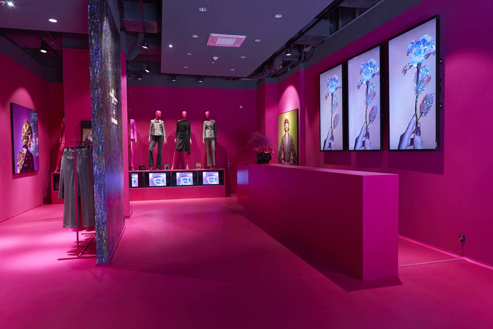 Pinker Innenraum eines Modeladens mit Postern, Bildschirmen, und Mannequins
