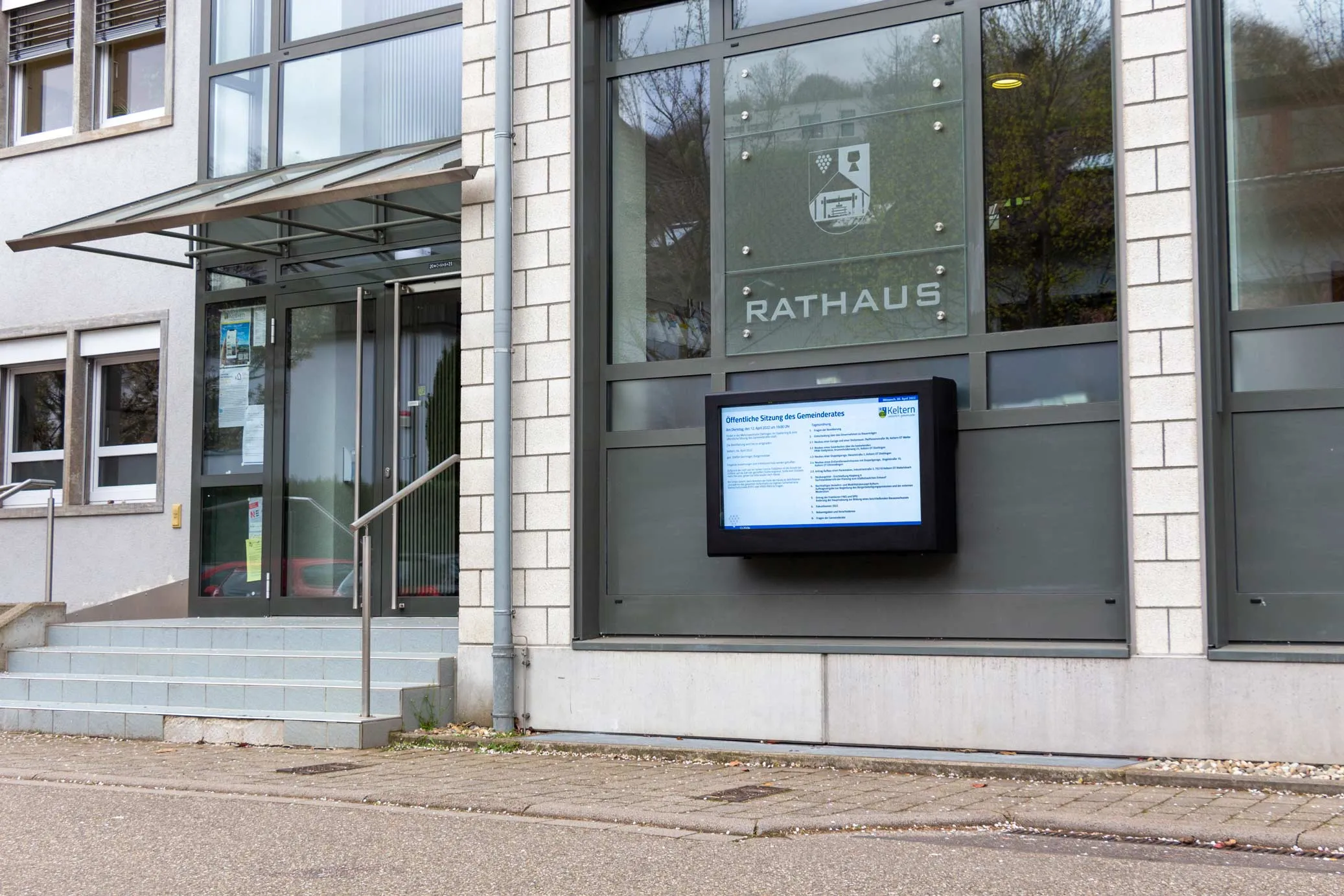 Digitaler Schaukasten vor einem Rathaus
