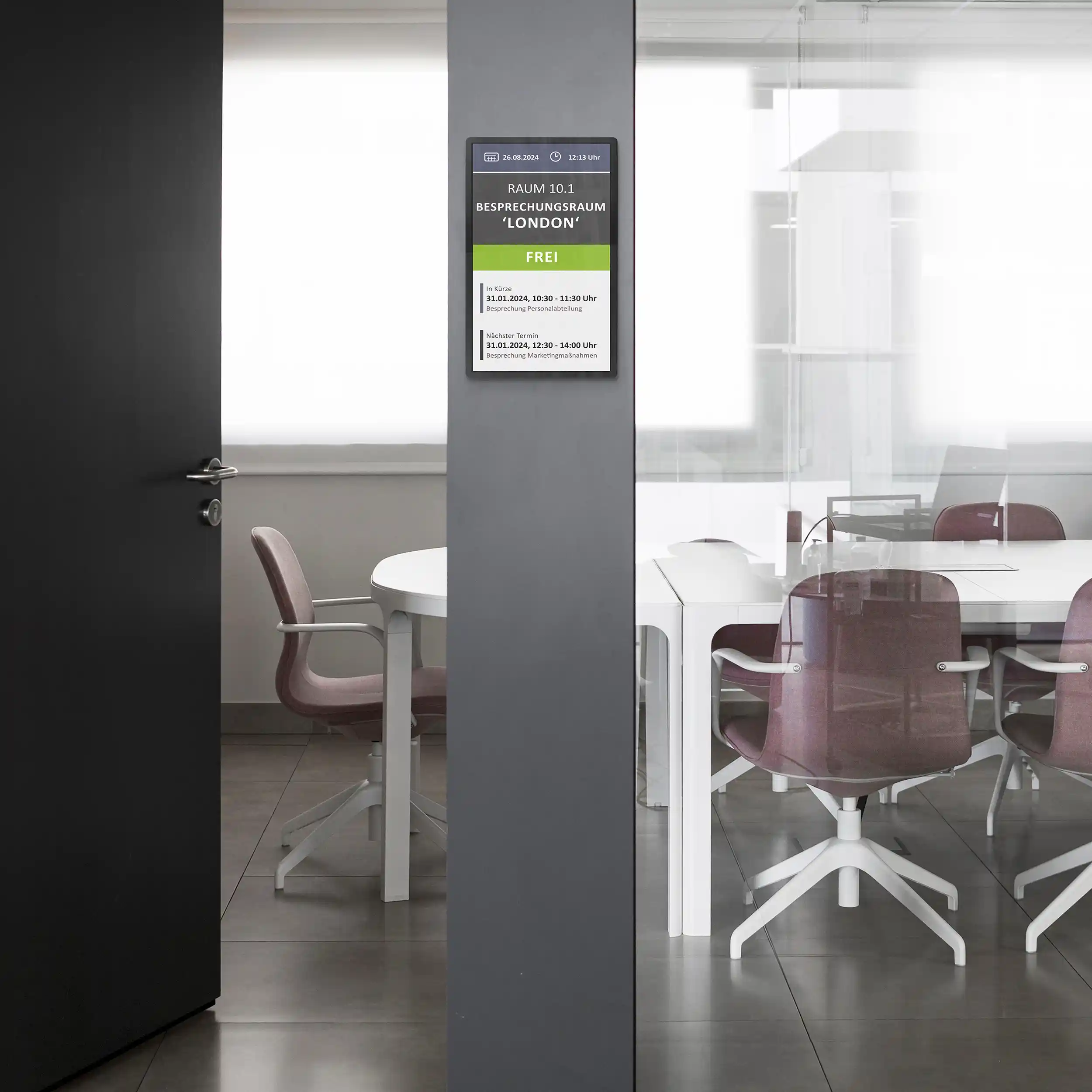 Moderner Besprechungsraum 'London' mit geöffnetem Tür, weißen Tischen und rosafarbenen Drehstühlen, digitale Türbeschilderung zeigt Verfügbarkeit.