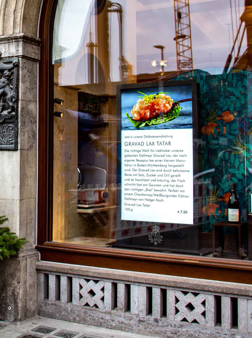 Schaufenster mit einem Display, das eine Anzeige für Gravad Lax Tatar mit Bild und Beschreibung zeigt.