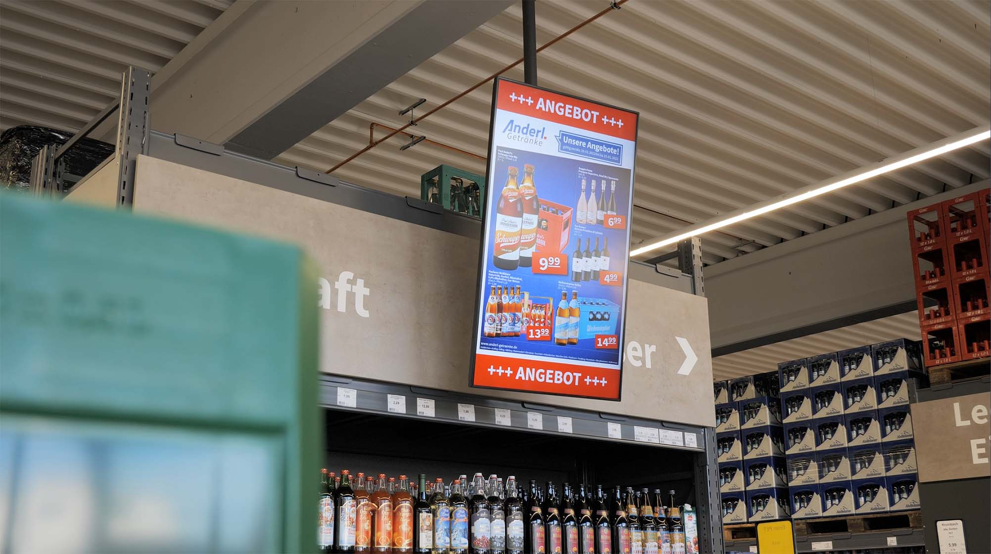 Digitales Angebotsplakat in einem Getränkemarkt zeigt Sonderangebote für verschiedene Getränke.