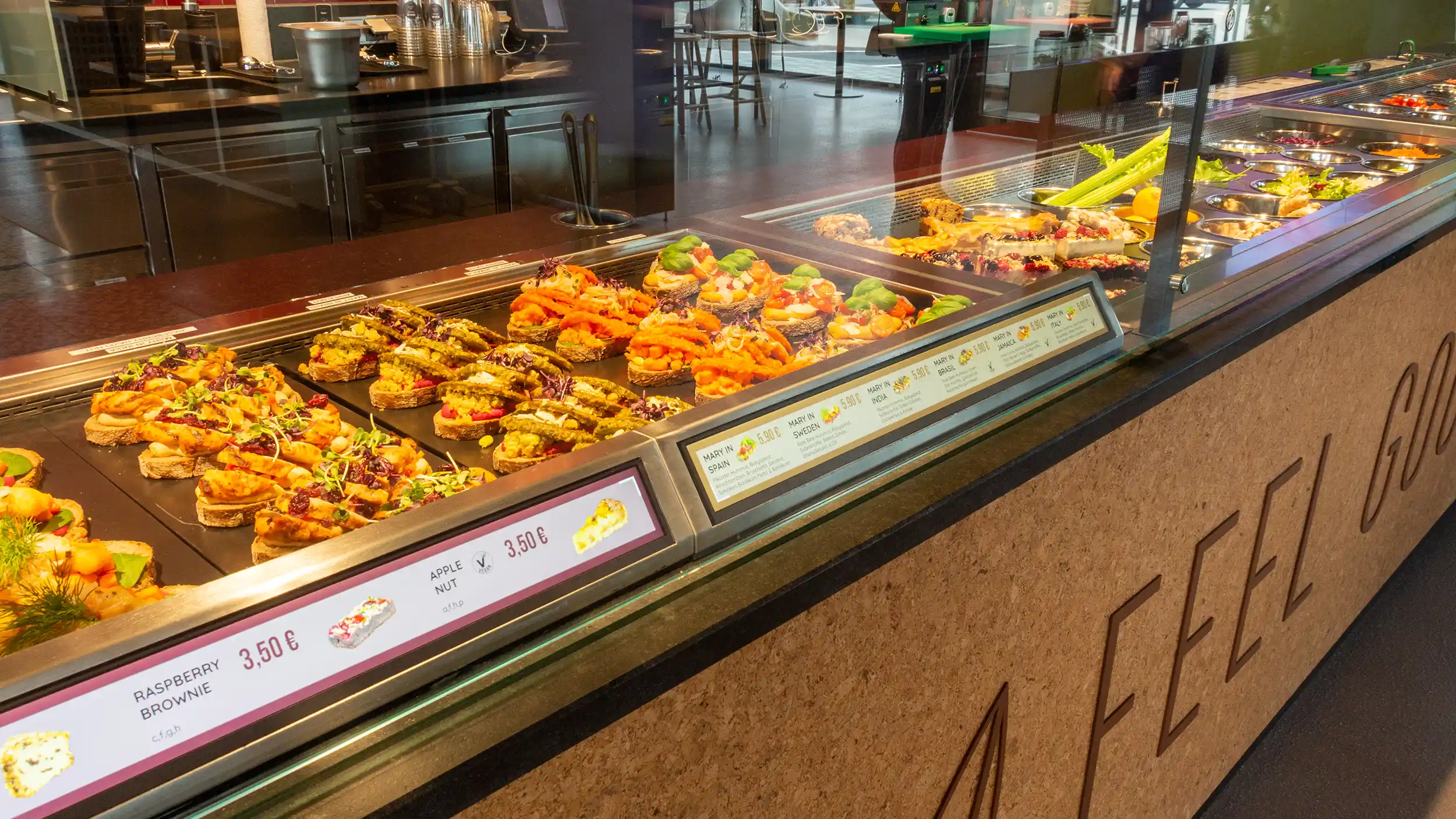 Bunte belegte Brotscheiben und Desserts in einer modernen Theke eines Cafés oder Bistros.