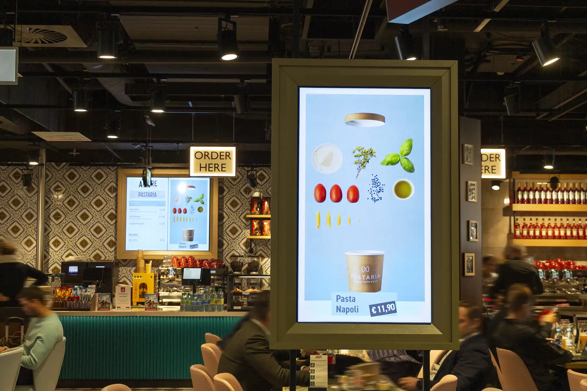 Digitale Speisekarte in einem Restaurant mit Zutatenabbildungen für Pasta Napoli und Preisanzeige von 11,90 Euro.