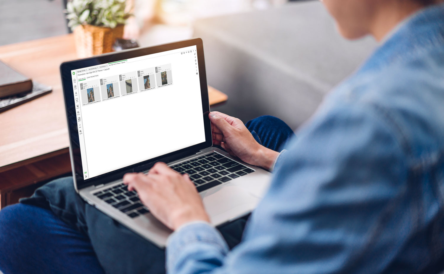 Person, die auf einem Laptop eine digitale Signage-Software mit Video-Promotionen auf dem Bildschirm verwendet.