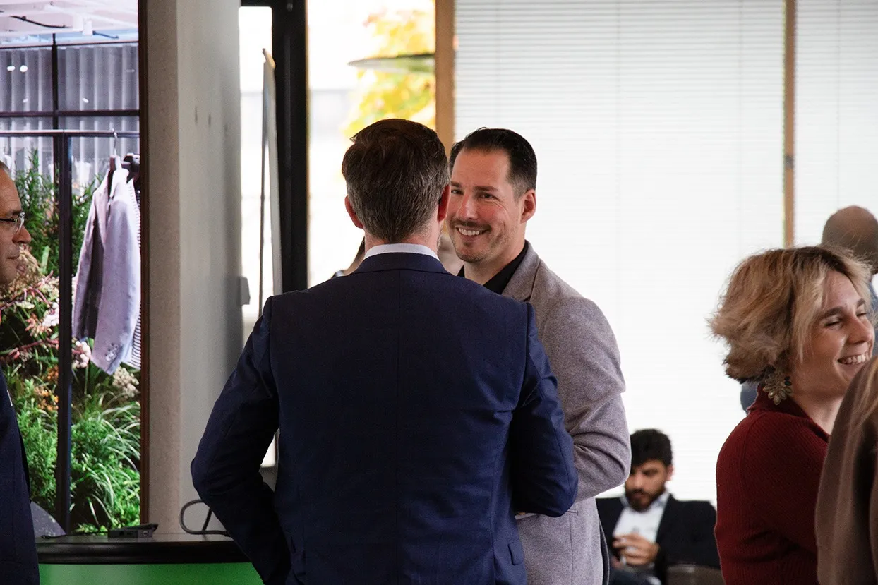 Menschen im Gespräch in einem hellen, modernen Innenraum mit Anzügen und legerer Kleidung.