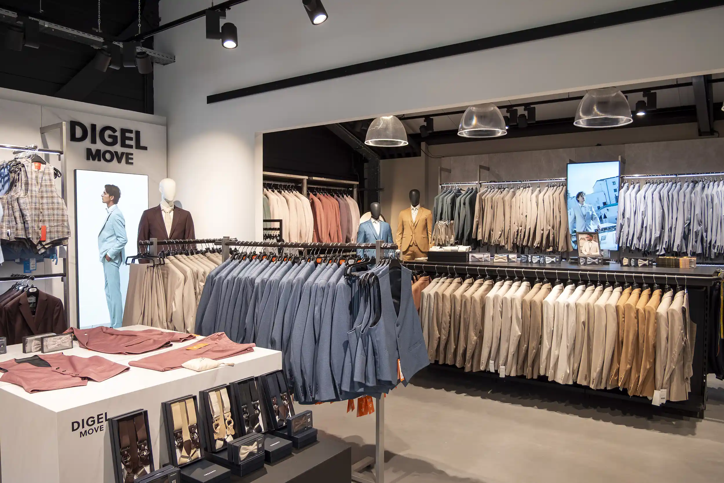 Herrenbekleidungsladen mit Anzügen, Westen und Accessoires, beleuchtet und Digital Signage Screens.