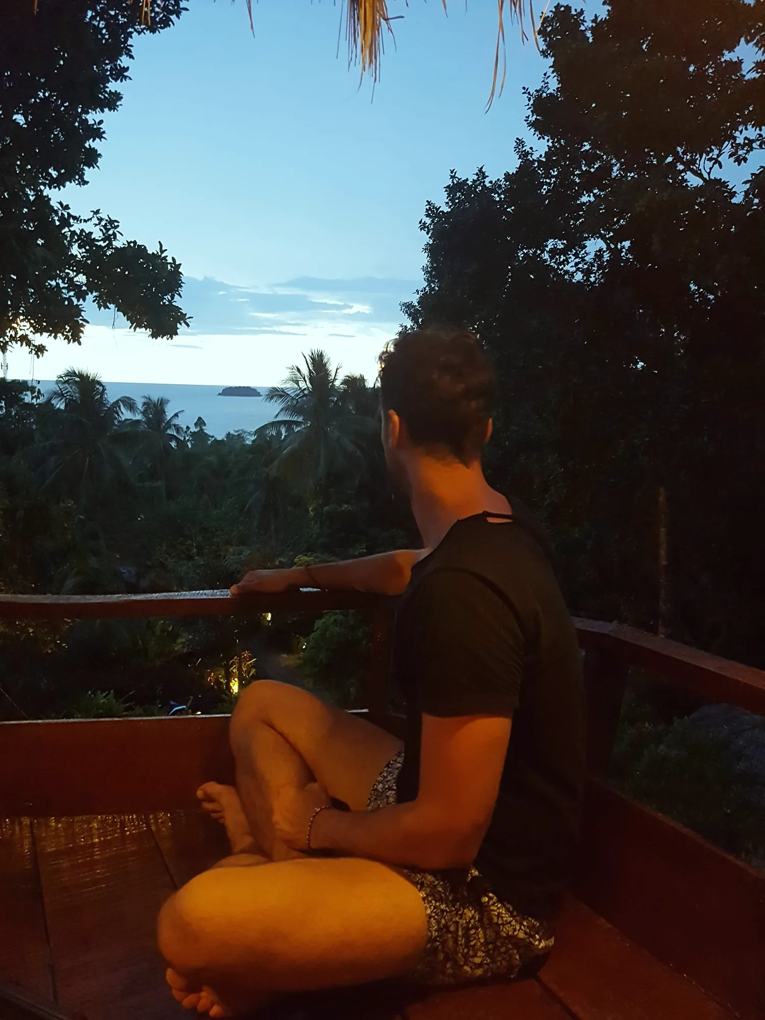 Amar seduto di spalle su una terrazza a Koh Chang, al tramonto