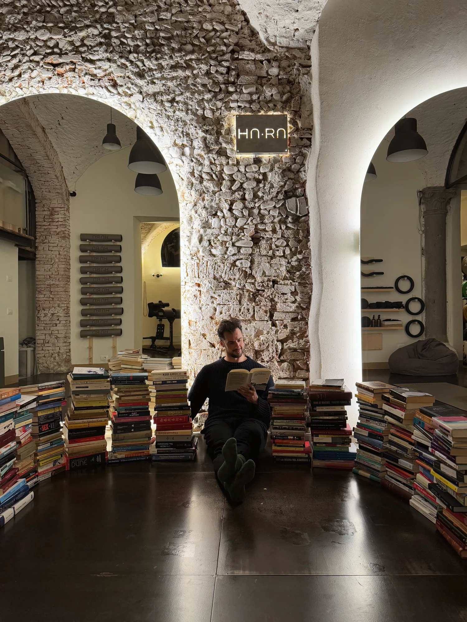 Amar seduto per terra a HARA, circondato da pile di libri