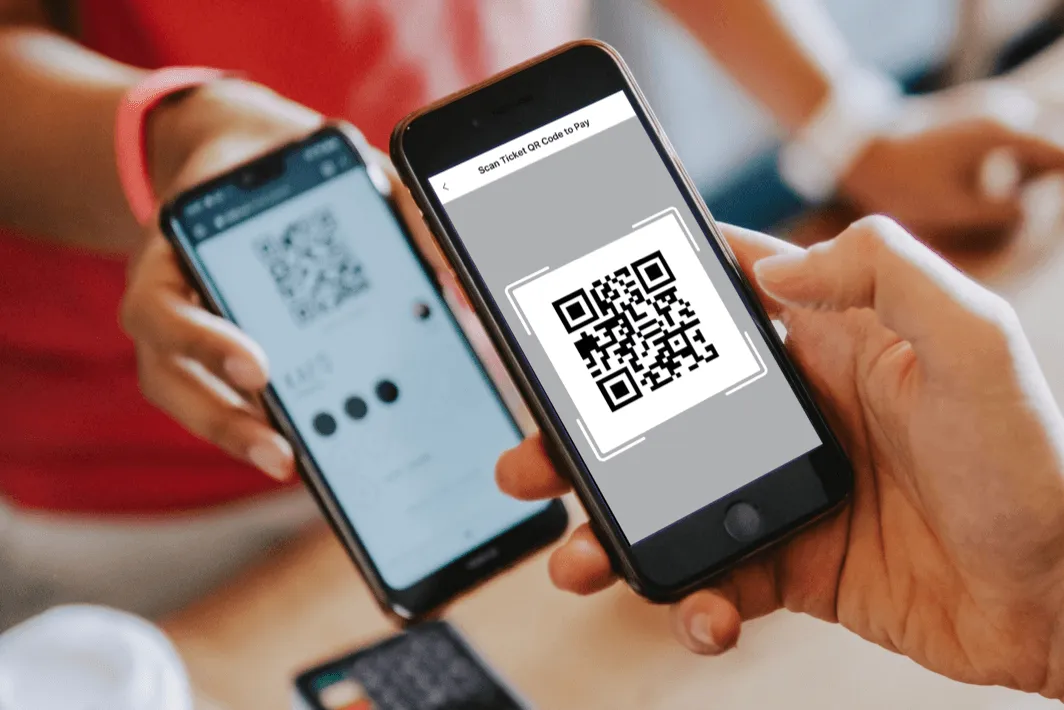 Two hands holding smartphones, one displaying a QR code and the other scanning it for payment.