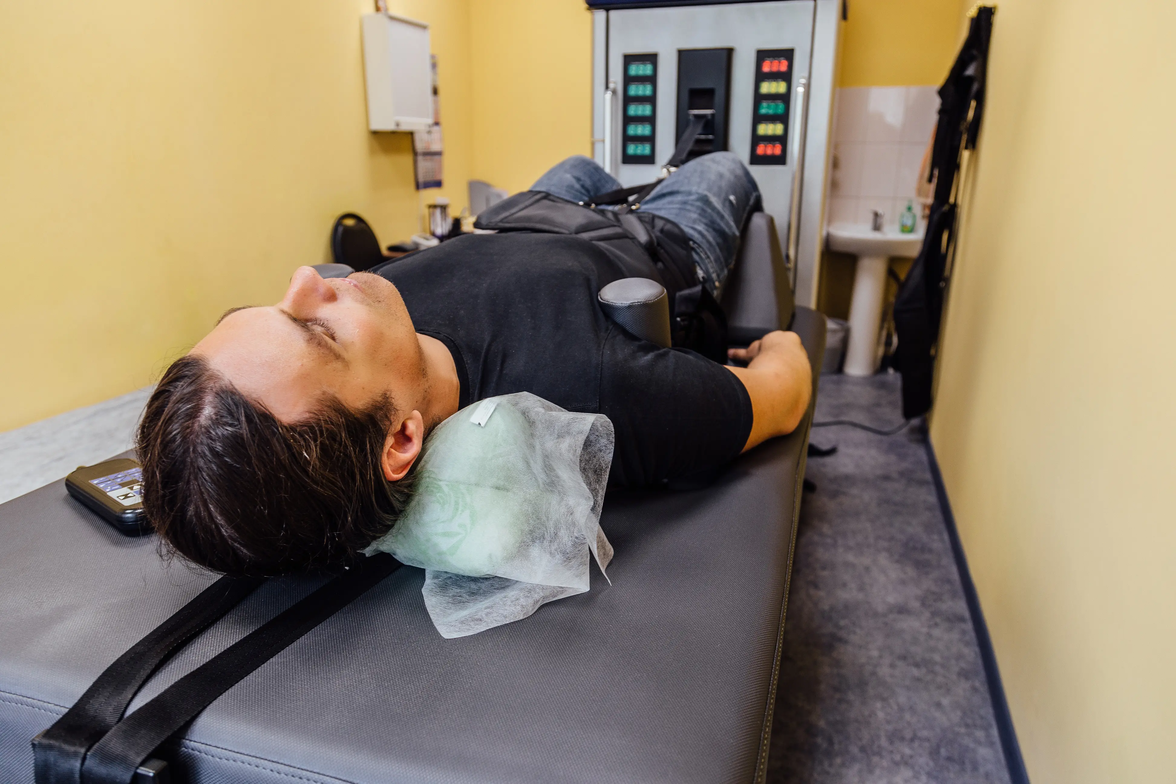 A close-up of a patient lying on a spinal decompression table, with a protective pad under their neck and a strap over their torso, highlighting a part of the treatment process for spinal issues.