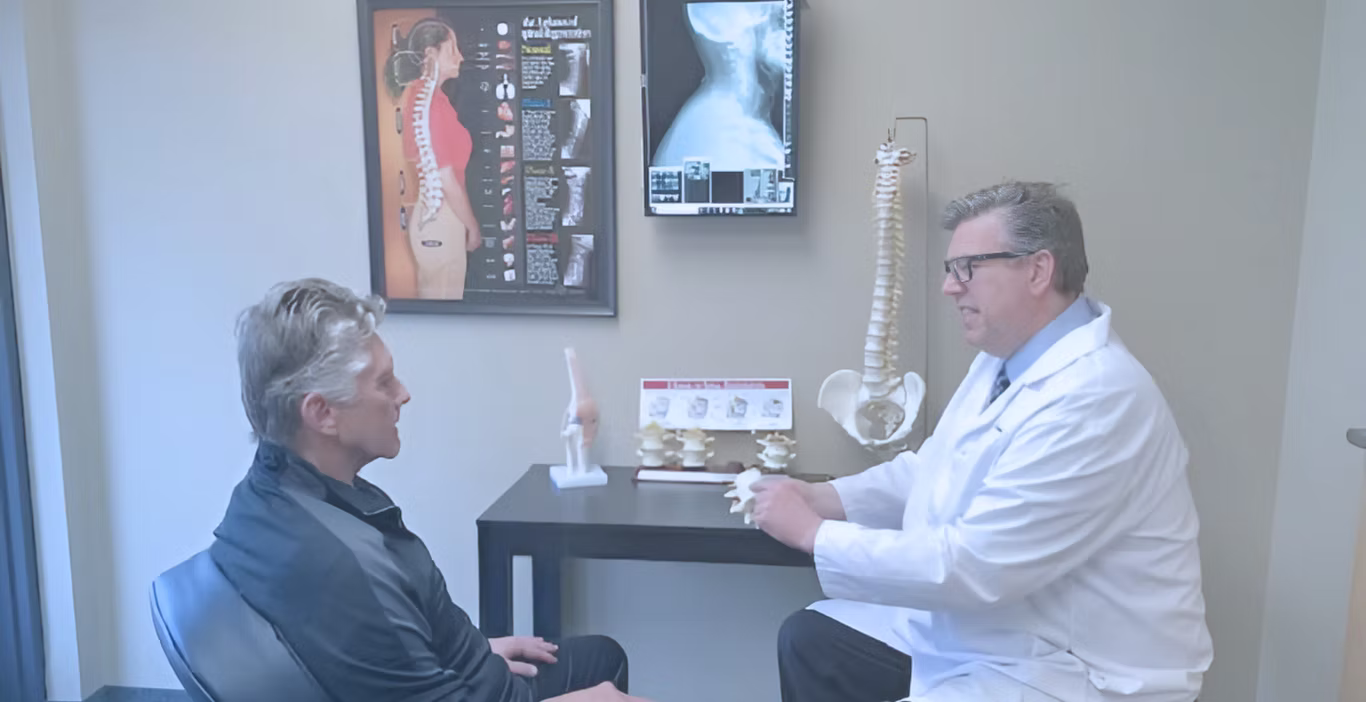 A chiropractor is performing a hip alignment or back adjustment on an elderly patient lying on their side on a treatment table, demonstrating a hands-on therapeutic procedure.