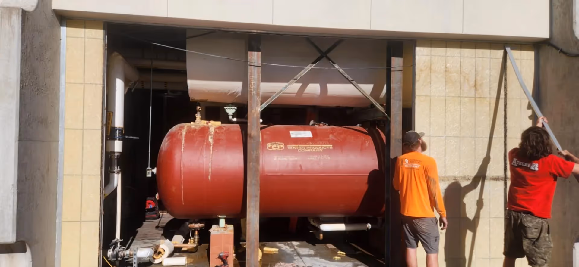 Back view of a technician guiding a tall cylindrical tank into place