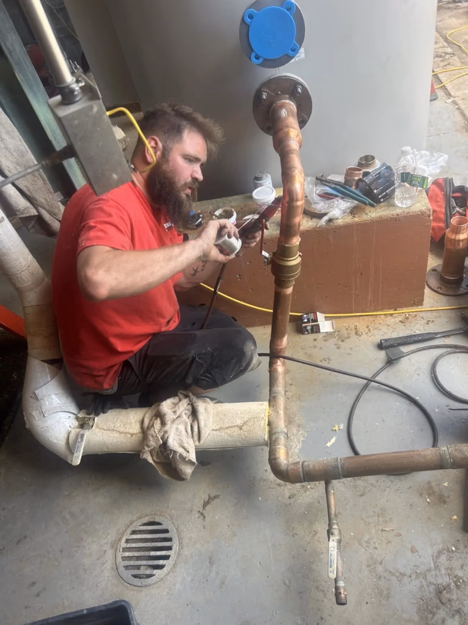 Large cylindrical water storage tank being lifted by straps during installation.