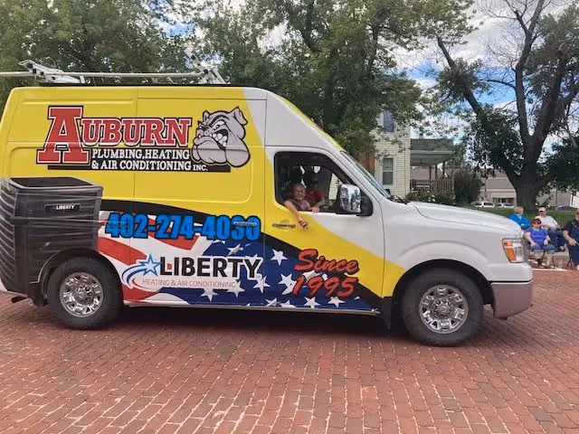 Service van decorated with stars and stripes design reading Liberty on a brick street.
