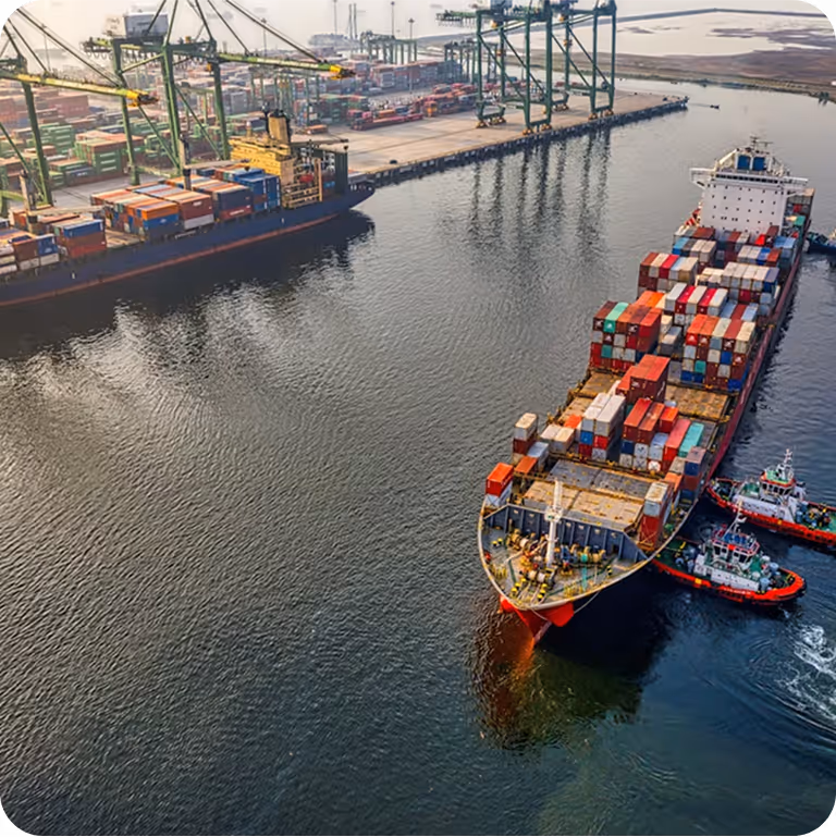 A large ship carrying shipping crates on ocean water as it leaves port.