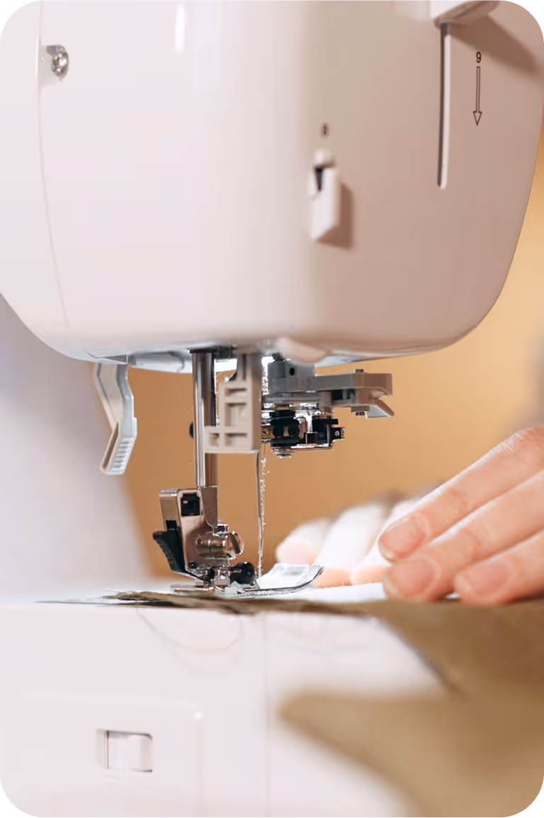 Close-up image of a sewing machine sewing a light fabric