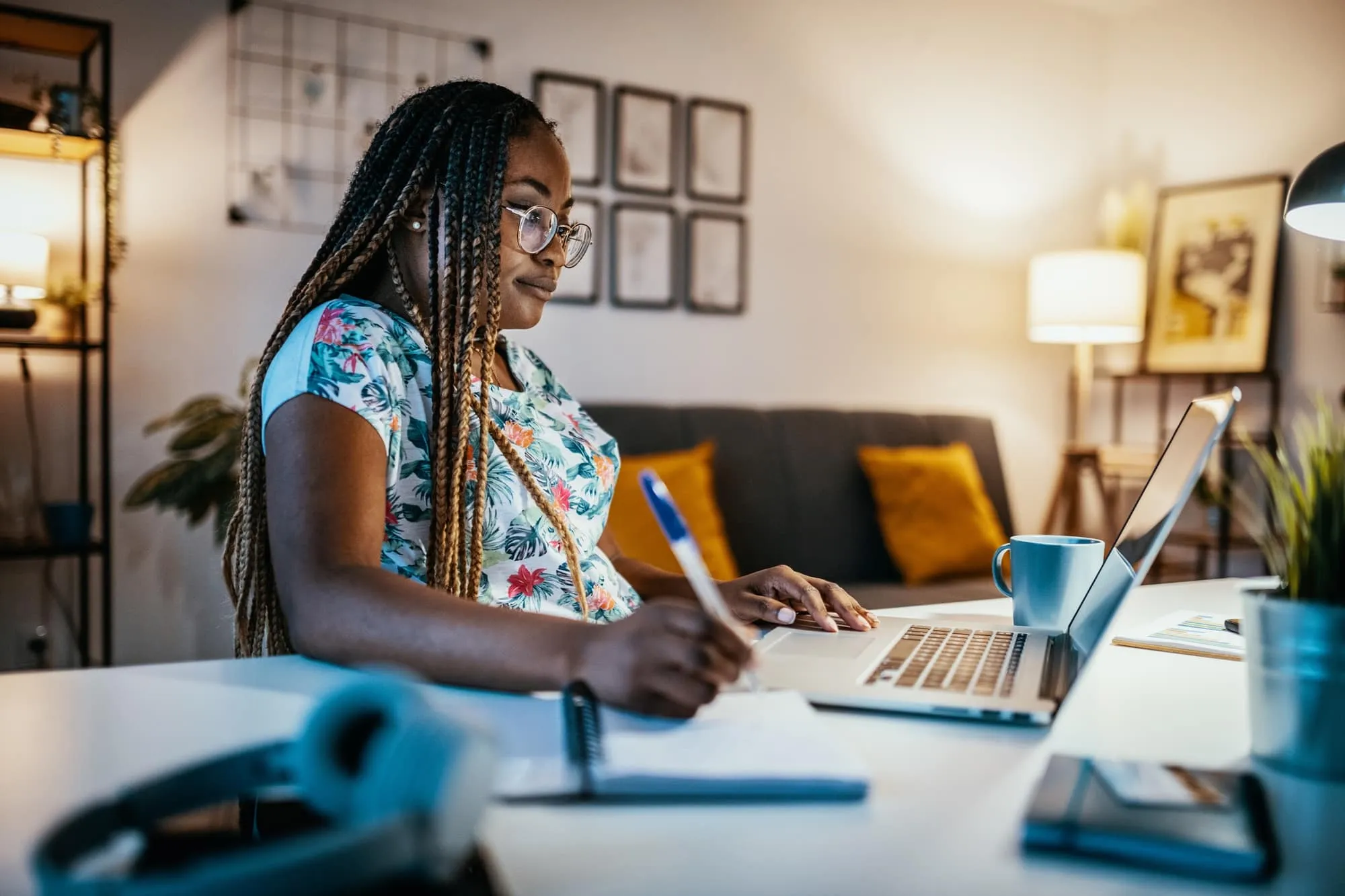 African American Female Student Studying From Home and Taking Notes from Professor