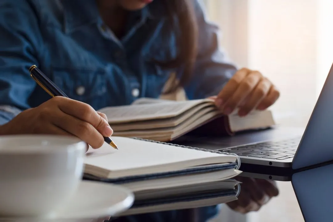 Person sitting at a table writing in a notebook