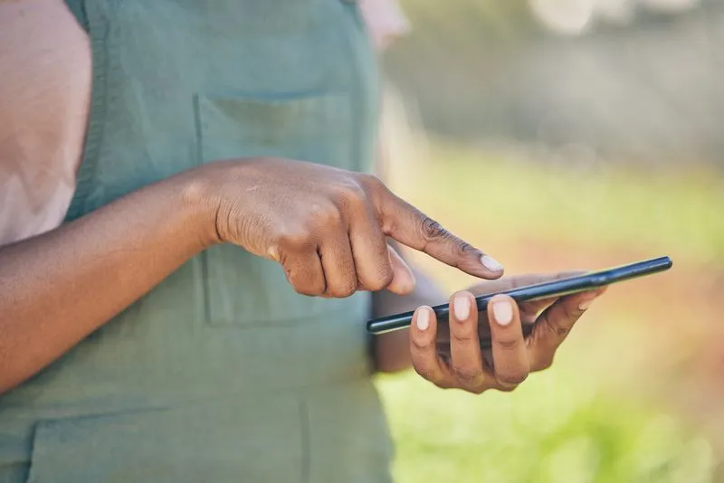 Women standing holding a cellphone with tapping using other hand