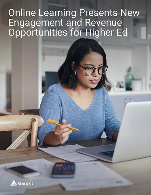 Women with dark hair and glasses sitting at a desk looking at a laptop computer