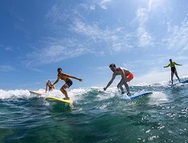 Cuatro personas surfeando olas en el océano bajo un cielo parcialmente nublado Guaycura Hotel Todos Santos