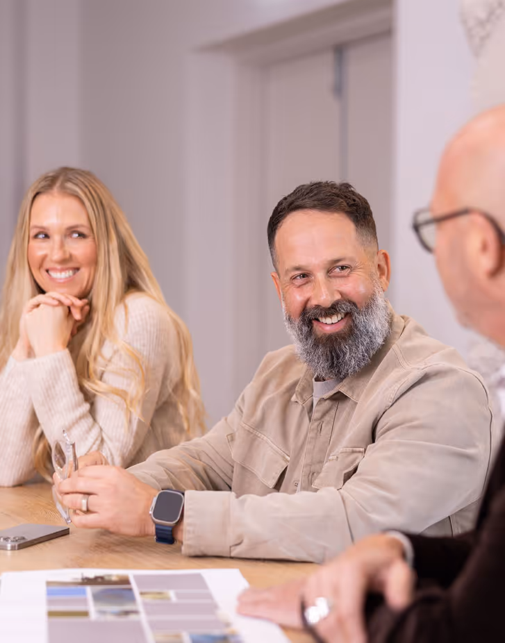 Three adults having a friendly conversation around a table with papers and a smartphone.