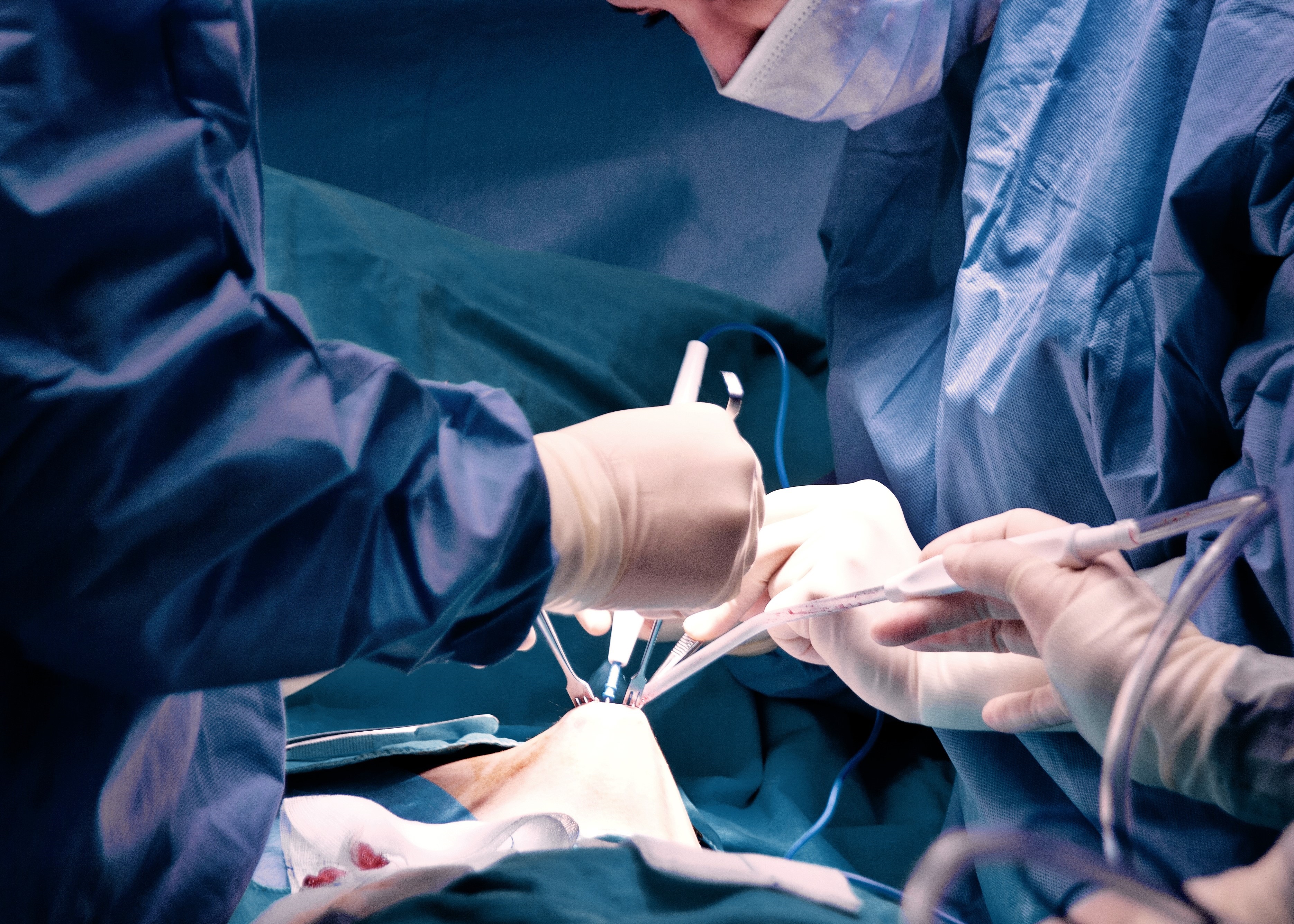 Two surgeons performing surgery on a patient in a hospital.