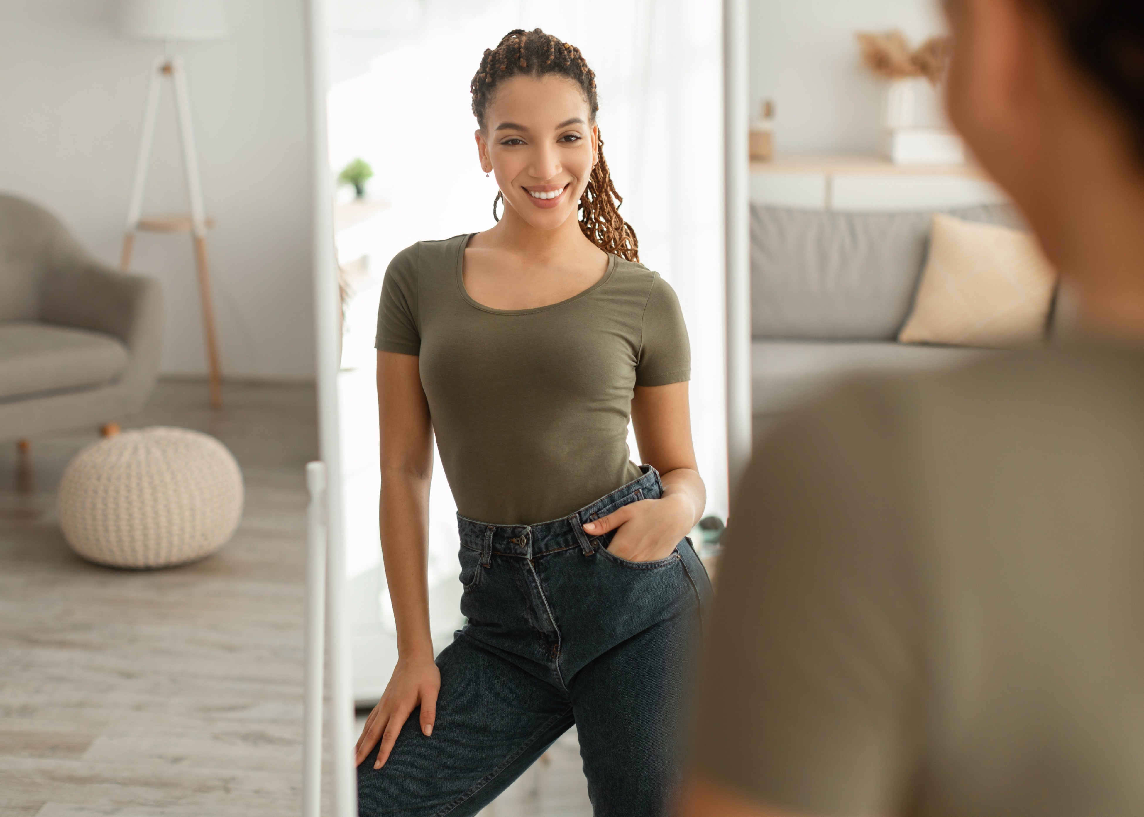 A woman looking in the mirror at her weight loss