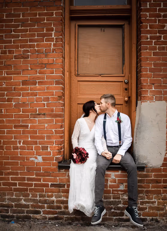 a couple taking wedding photos in front of a brick building