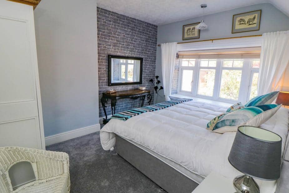 Double bed with white duvet beside large bay window