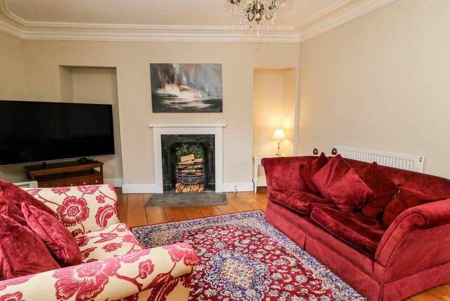 Cottage lounge with red sofas, fireplace and patterned rug