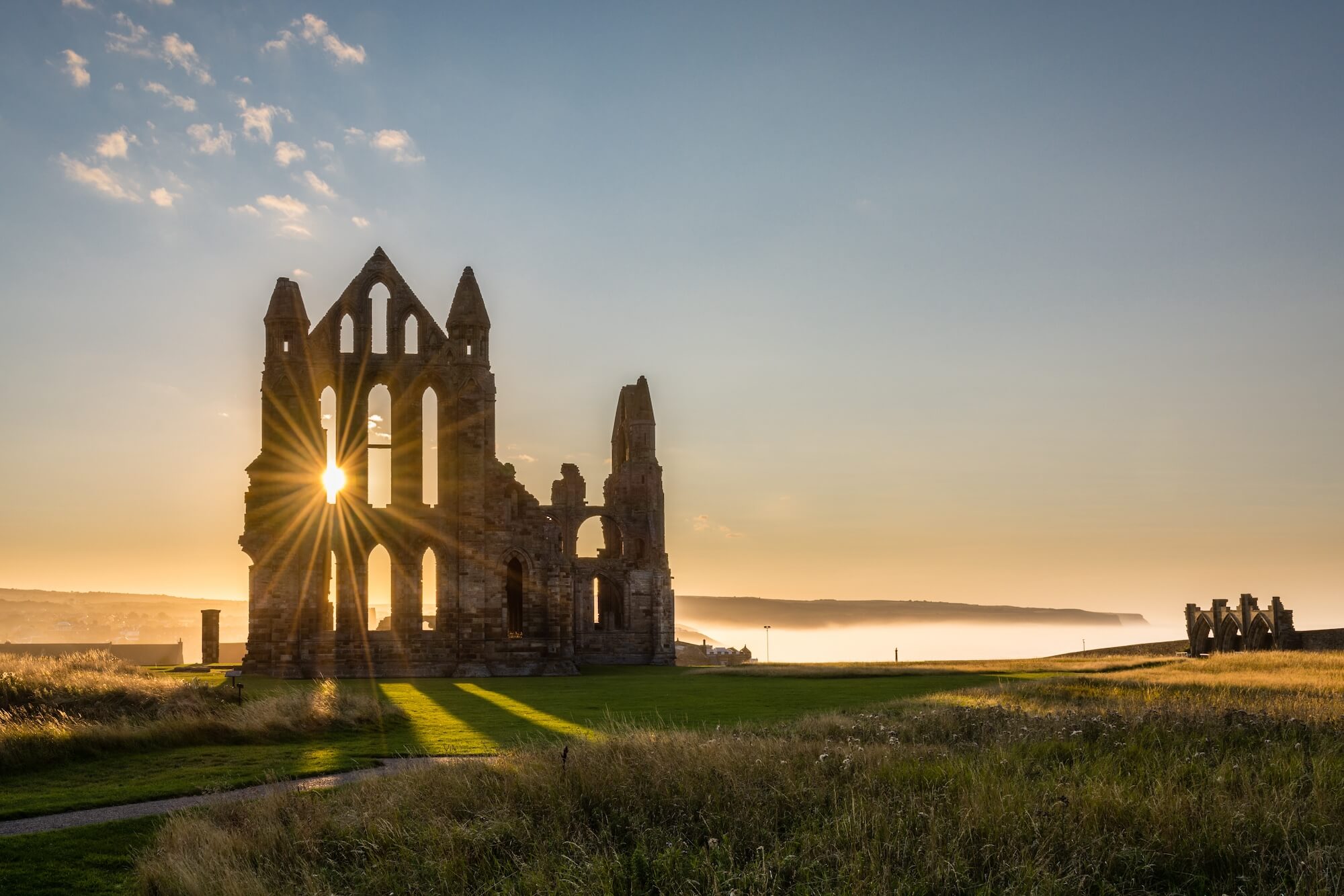 Golden sunburst shining through the ancient ruins of Whitby Abbey
