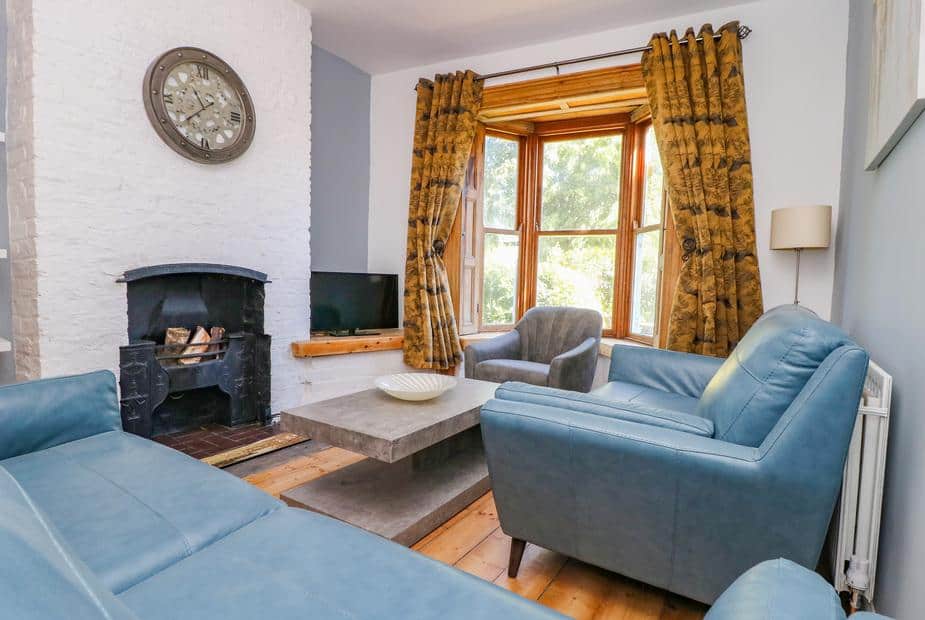 Living room with blue sofas, bay window and wood-burning stove