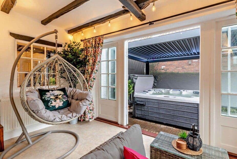 Lounge with hanging chair and doors opening to covered hot tub area