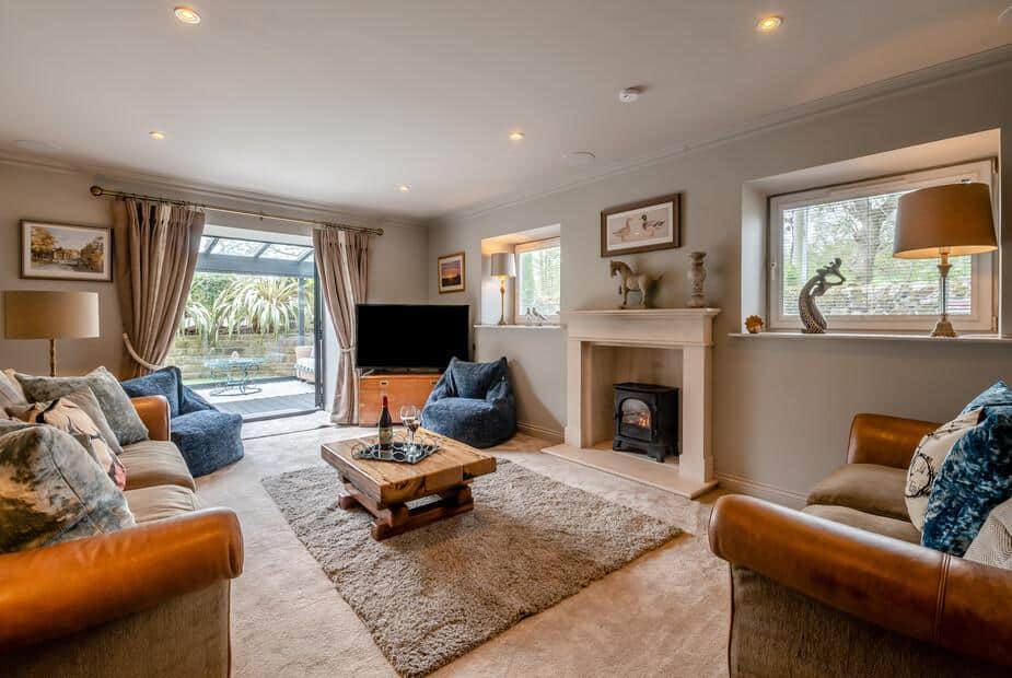 Cottage lounge with fireplace, TV and doors opening to patio garden