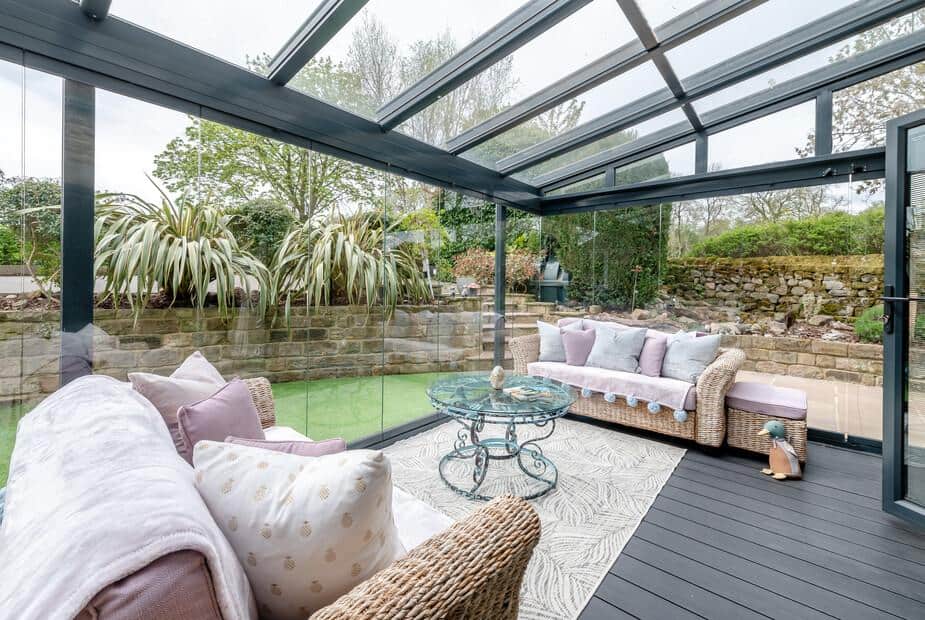 Cottage conservatory with wicker sofas and glass coffee table overlooking garden