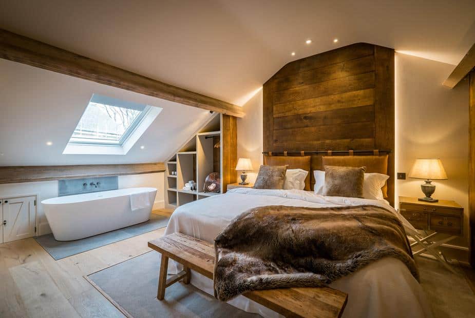 Cottage bedroom with double bed and freestanding bath under skylight